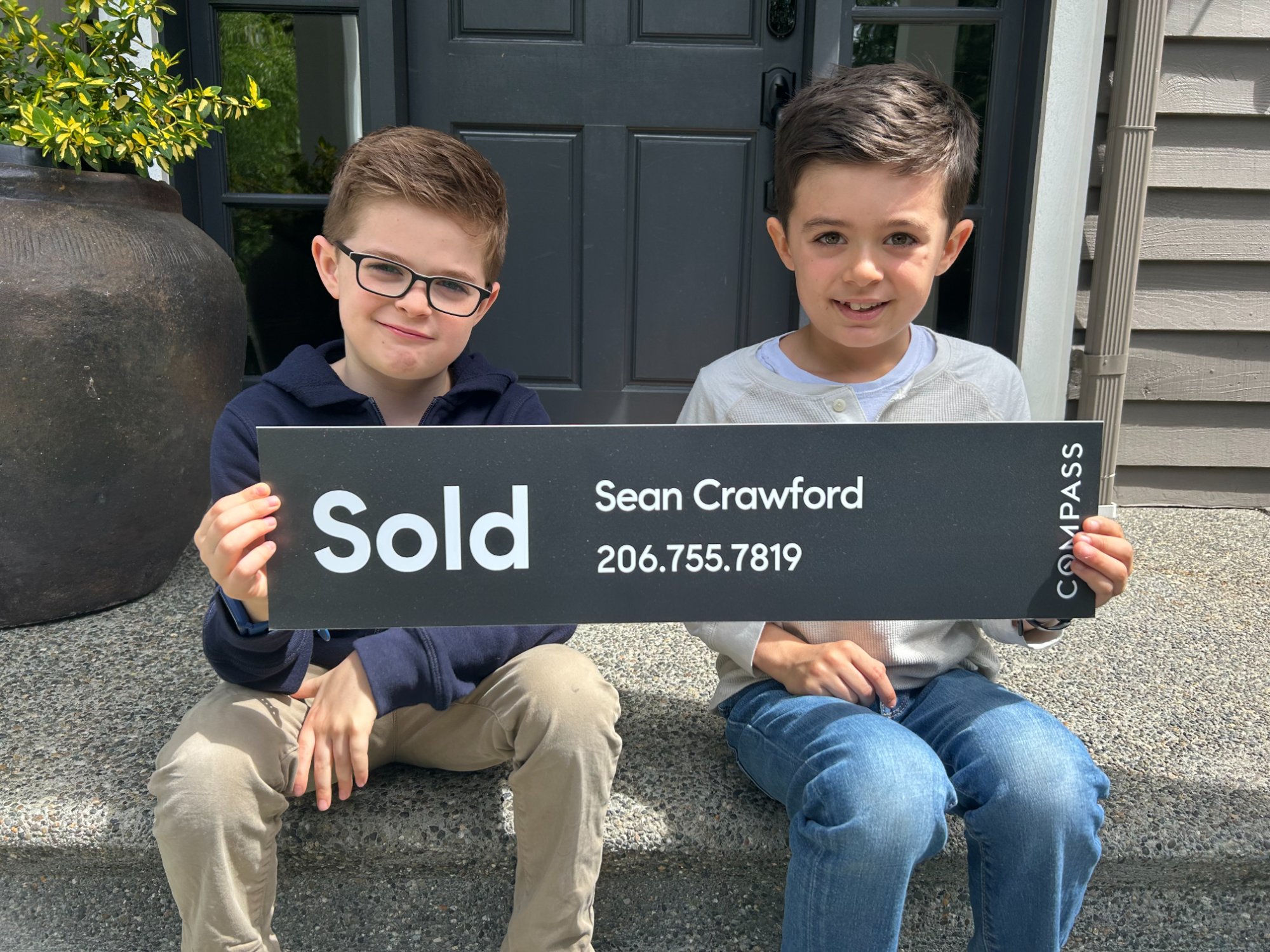 Sean's twin sons holding a Compass Sold sign